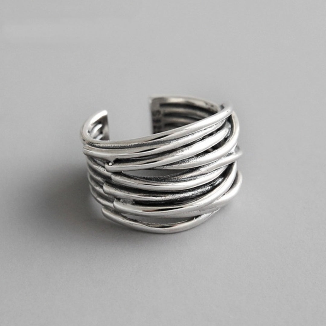 The 925 Sterling Silver Adjustable Layered Ring features overlapping, curved bands in a stunning handcrafted design. This open-ended silver ring is showcased on a plain, light gray background.