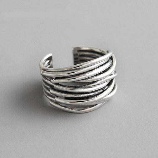 The 925 Sterling Silver Adjustable Layered Ring features overlapping, curved bands in a stunning handcrafted design. This open-ended silver ring is showcased on a plain, light gray background.