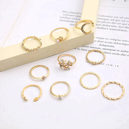 A 10 pack of Bohemian silver and gold plated rings with various textures and designs, featuring pearls and small stones, arranged on a white surface with a beige frame in the background.