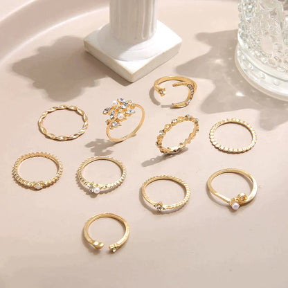 A 10 pack of Bohemian silver and gold plated rings with assorted designs, some adorned with small pearls or crystals, displayed on a beige surface near decorative accents.