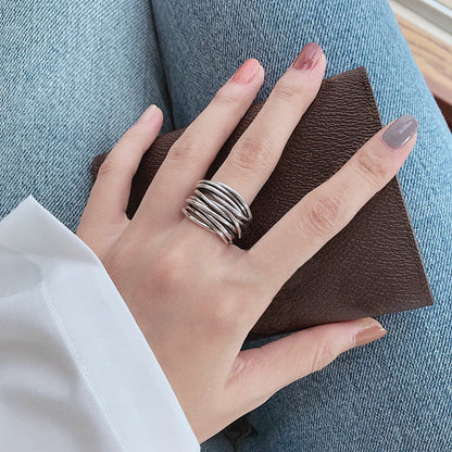 A hand with neatly manicured nails wears our 925 Sterling Silver Adjustable Layered Ring and holds a textured brown wallet, styled with blue jeans and a white shirt.