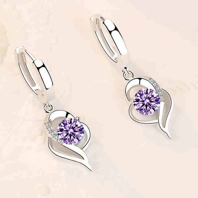 The 925 Sterling Silver and Zirconia Inlaid Floral Earrings feature a leaf-inspired design with a round purple zirconia center and sparkling clear accents, handcrafted and displayed on a light, neutral background.