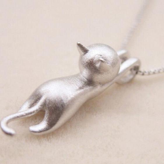 The 925 Sterling Silver Playful Kitty Necklace features a minimalist cat pendant with a curved tail and pointed ears, elegantly handcrafted and hanging from a fine chain against a light background.