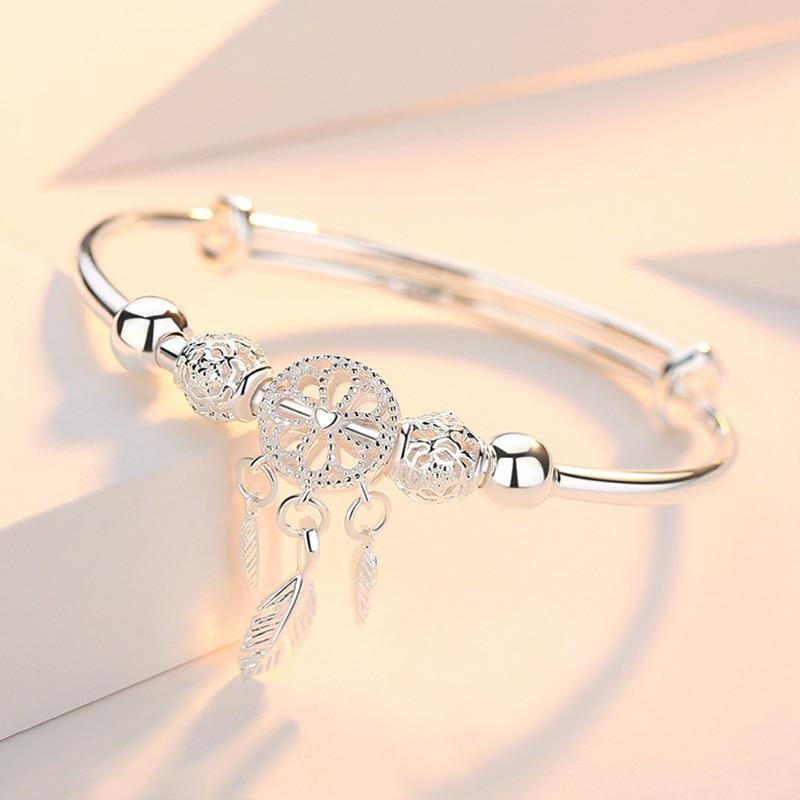 The 925 Silver Adjustable Dreamcatcher Bracelet features a central dreamcatcher charm with three feather charms and two decorative beads, all handcrafted and displayed on a soft pastel background.