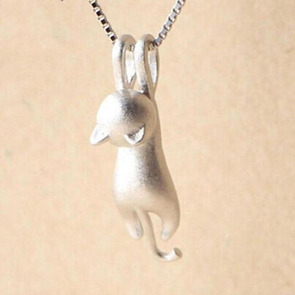 The 925 Sterling Silver Playful Kitty Necklace features a minimalist cat pendant with distinct head, ears, and curled tail on a chain, showcased against a plain beige background. This handcrafted piece is perfect for cat lovers.